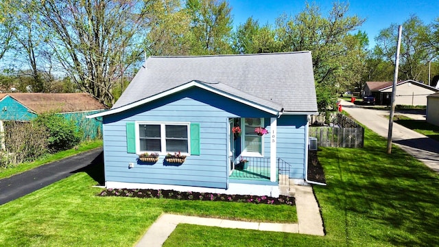 bungalow with fence, a front yard, and a shingled roof