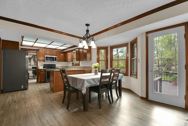 dining space with an inviting chandelier, crown molding, baseboards, a textured ceiling, and light wood finished floors