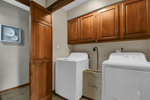 washroom featuring washer and dryer, baseboards, wood finished floors, and cabinet space
