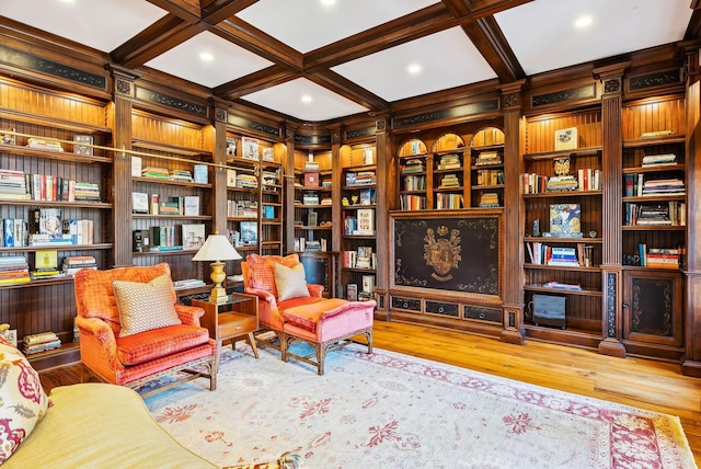 living area with beamed ceiling, built in shelves, wood finished floors, and coffered ceiling