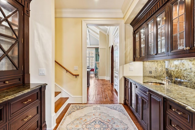 bar with ornamental molding, dark wood-style flooring, baseboards, tasteful backsplash, and a sink