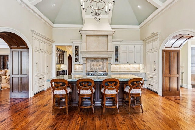 kitchen featuring light stone counters, arched walkways, and high vaulted ceiling