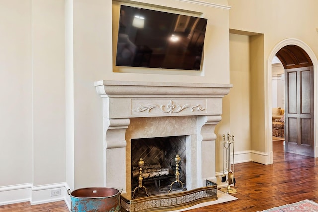 room details with baseboards, arched walkways, wood finished floors, and a premium fireplace