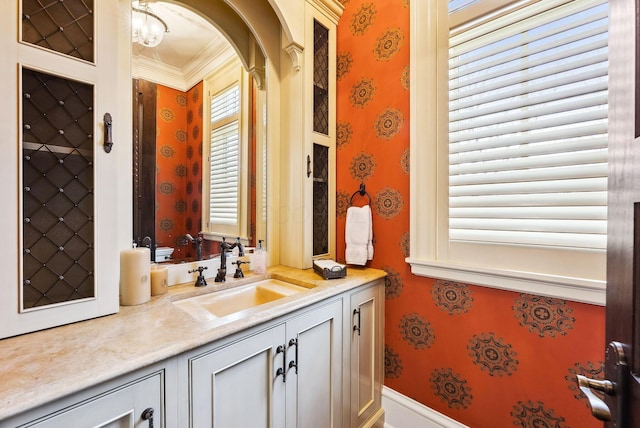 bathroom with wallpapered walls, ornamental molding, and vanity