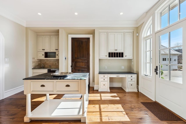 kitchen featuring crown molding, baseboards, and wood finished floors