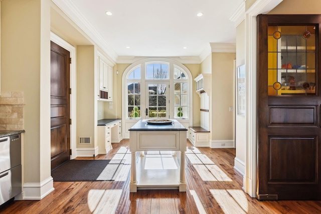 doorway with crown molding, visible vents, baseboards, light wood-type flooring, and recessed lighting