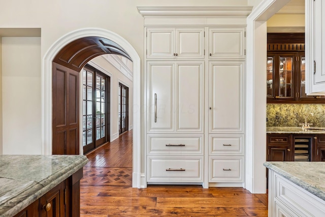 interior space with decorative backsplash, french doors, wet bar, arched walkways, and wine cooler