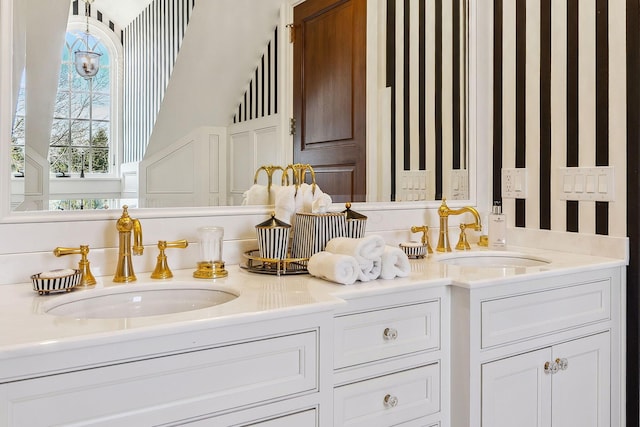 bathroom featuring a sink, wallpapered walls, and double vanity