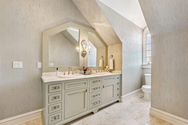 bathroom featuring double vanity, a sink, vaulted ceiling, and toilet