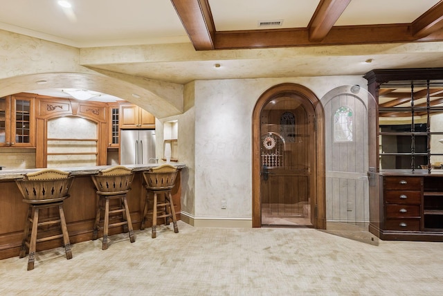 bar featuring high end fridge, light colored carpet, arched walkways, beamed ceiling, and visible vents