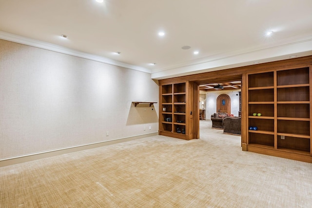 below grade area featuring ceiling fan, ornamental molding, baseboards, and carpet