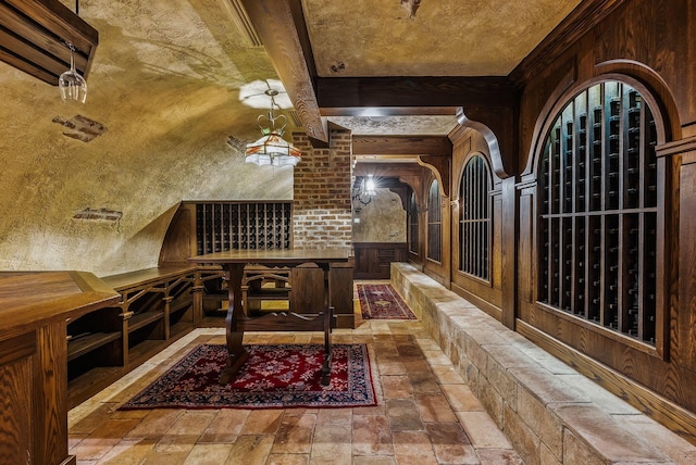 wine room featuring stone tile flooring, beam ceiling, and wooden walls