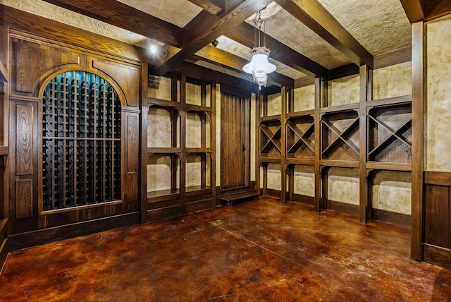 wine area with concrete flooring and beam ceiling