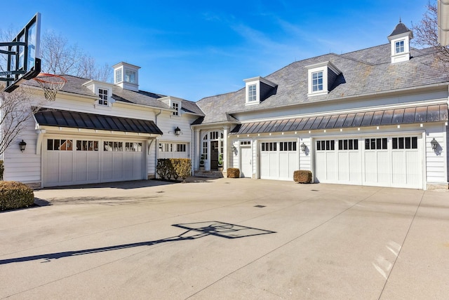 view of front facade featuring metal roof, a high end roof, a standing seam roof, and concrete driveway