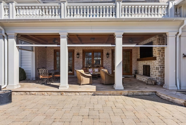view of patio / terrace with a balcony and an outdoor living space with a fireplace