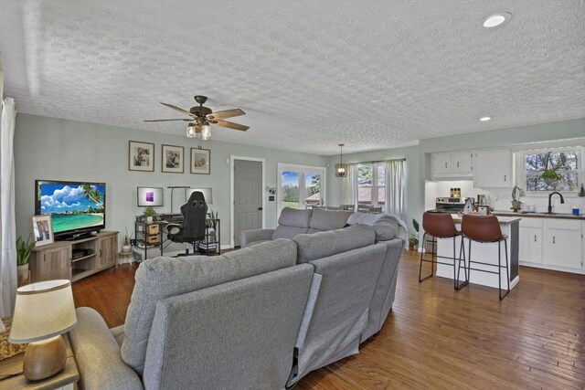 living area with recessed lighting, a ceiling fan, dark wood finished floors, and a textured ceiling