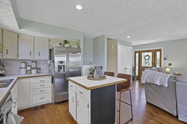 kitchen featuring a kitchen breakfast bar, dark wood finished floors, stainless steel appliances, open floor plan, and a kitchen island
