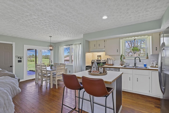 kitchen with dark wood-style flooring, a textured ceiling, decorative backsplash, and a sink