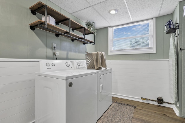 washroom featuring laundry area, wood finished floors, baseboards, wooden walls, and washer and dryer