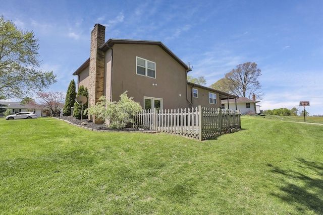 back of property featuring a lawn, fence, a chimney, and stucco siding