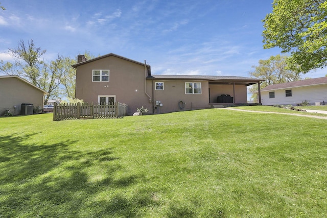 rear view of property with stucco siding, a yard, central AC, and a chimney