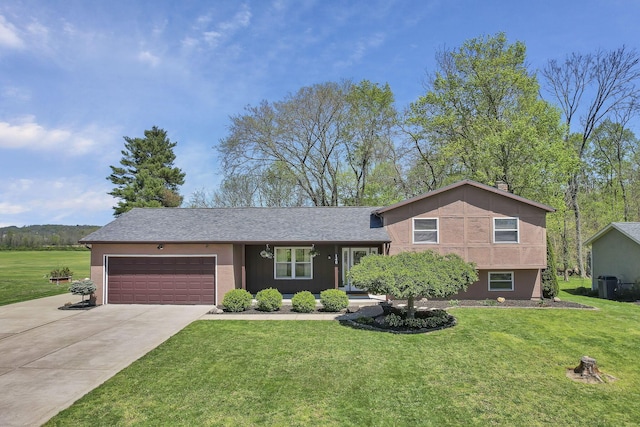 split level home featuring an attached garage, driveway, central AC, and a front lawn