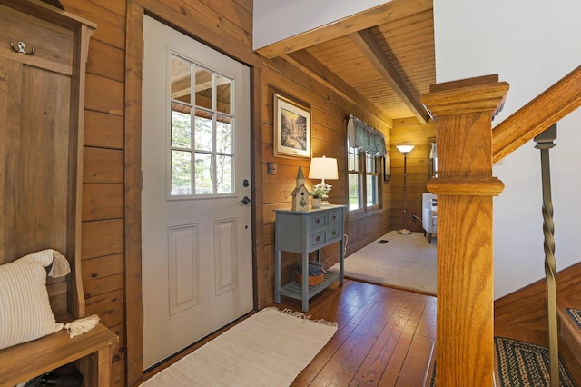 entryway featuring wood walls, beam ceiling, a wealth of natural light, and hardwood / wood-style floors