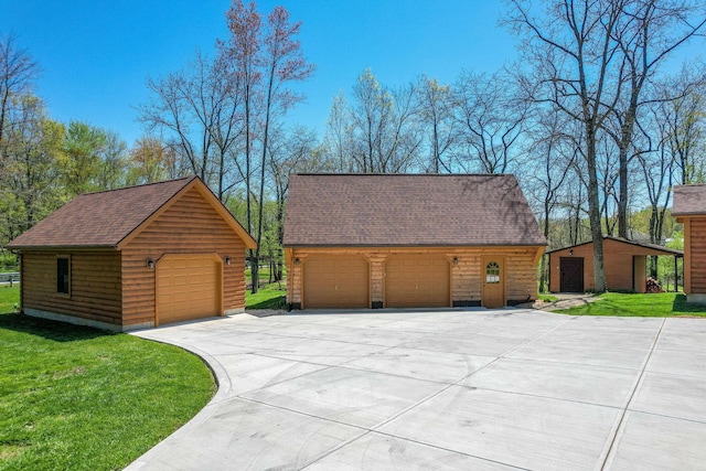 view of front facade featuring an outdoor structure, a garage, roof with shingles, and a front yard