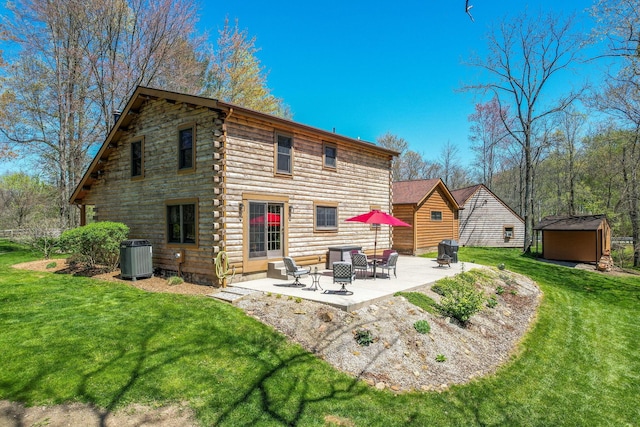 rear view of property with a storage unit, log exterior, an outbuilding, a lawn, and a patio