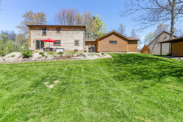 back of house with log siding, a yard, and a patio area
