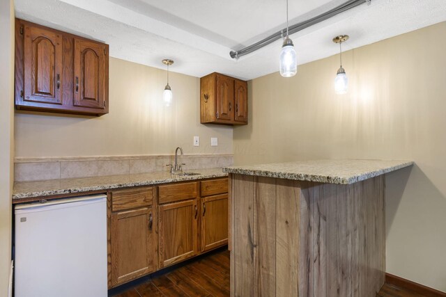 kitchen featuring a sink, brown cabinets, fridge, and dark wood finished floors