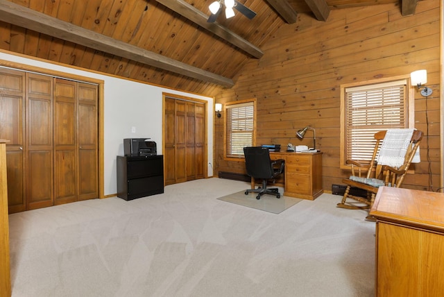 home office featuring vaulted ceiling with beams, a ceiling fan, wood walls, and light colored carpet