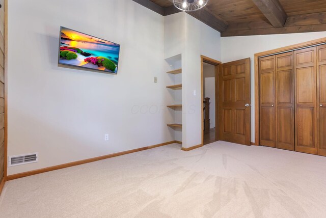 unfurnished bedroom with visible vents, vaulted ceiling with beams, wooden ceiling, and light colored carpet