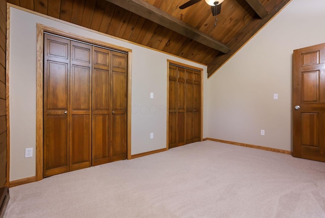 unfurnished bedroom with lofted ceiling with beams, carpet, and multiple closets