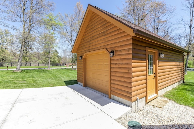detached garage featuring concrete driveway and fence