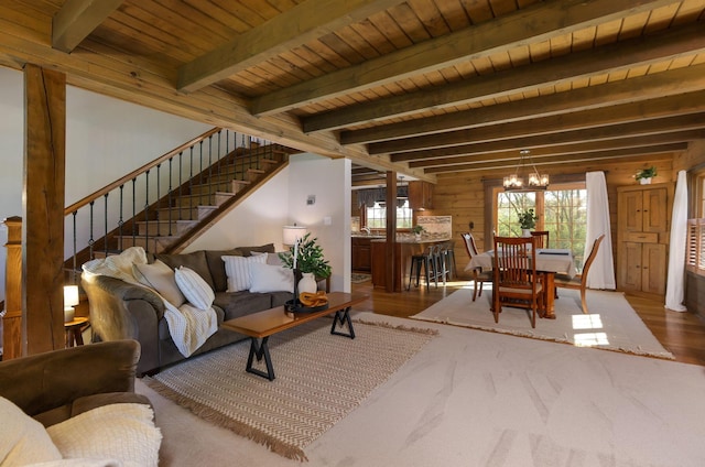 living room featuring an inviting chandelier, stairs, wood finished floors, beam ceiling, and wood ceiling