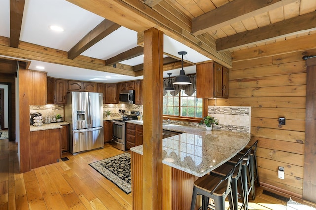 kitchen with appliances with stainless steel finishes, light wood-style floors, a peninsula, tasteful backsplash, and beamed ceiling
