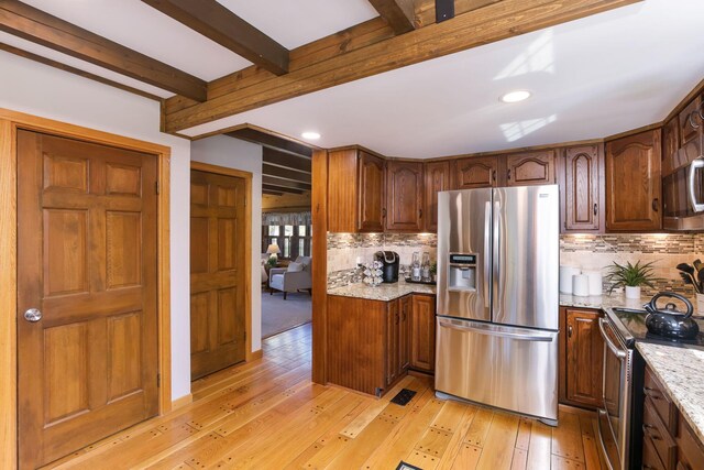 kitchen featuring light stone counters, backsplash, beam ceiling, and stainless steel appliances