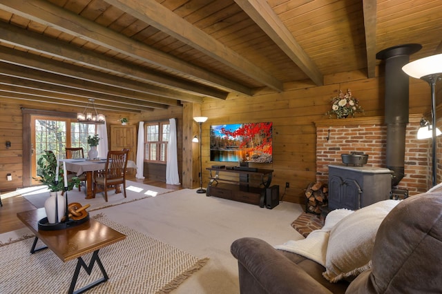living area with a wood stove, wood walls, beamed ceiling, a chandelier, and wooden ceiling