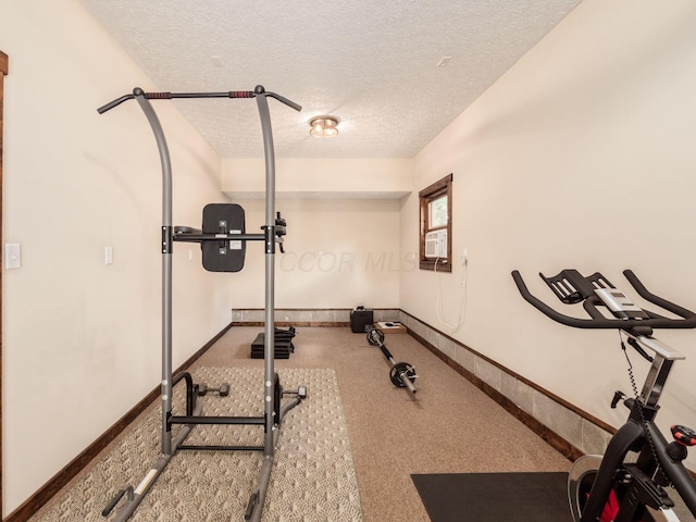 exercise room with carpet floors, a textured ceiling, baseboards, and cooling unit