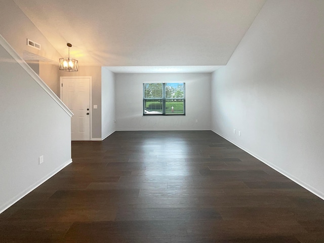 unfurnished living room with baseboards, dark wood-style flooring, a chandelier, and visible vents
