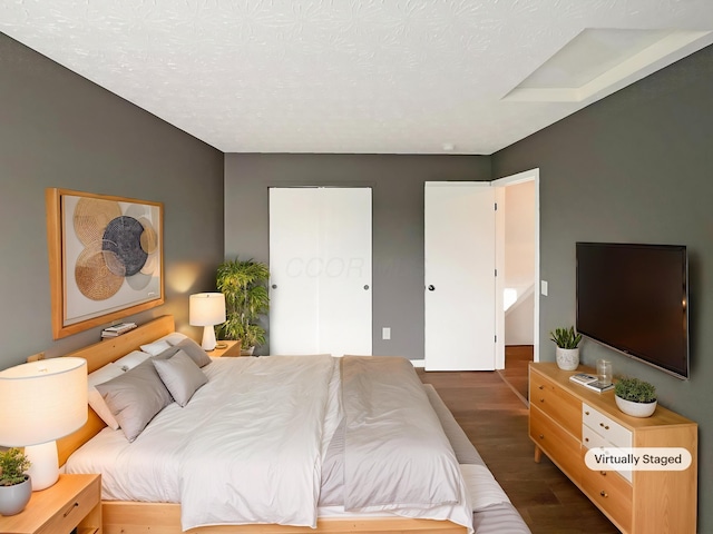 bedroom featuring a textured ceiling and dark wood finished floors