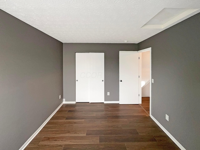 unfurnished bedroom with baseboards, a textured ceiling, and wood finished floors