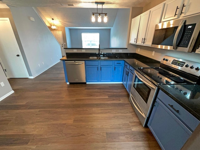 kitchen featuring dark wood-style flooring, a peninsula, white cabinetry, a sink, and stainless steel appliances