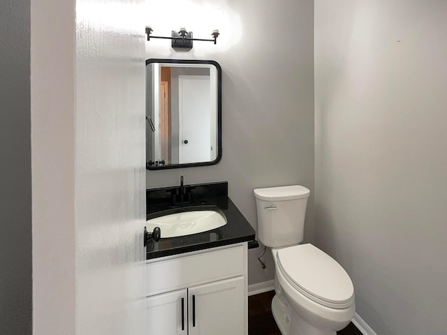 bathroom with baseboards, toilet, and vanity