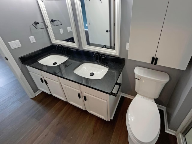 bathroom with double vanity, toilet, a sink, and wood finished floors