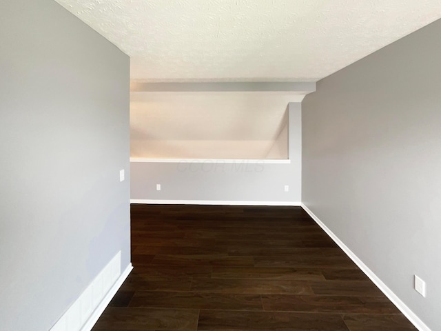 hallway with baseboards, a textured ceiling, and wood finished floors