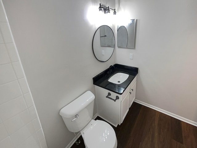 bathroom with toilet, baseboards, wood finished floors, and vanity