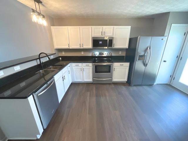 6330 Pompano St, Canal Winchester, OH 43110 - kitchen featuring appliances with stainless steel finishes, a sink, dark wood-type flooring, dark countertops, and white cabinetry