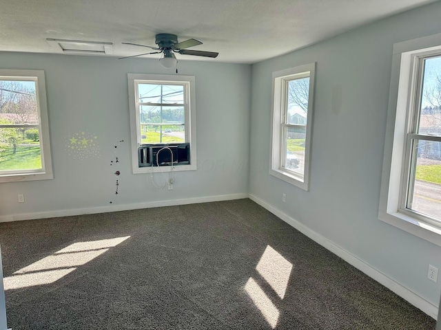 spare room featuring baseboards, dark colored carpet, and a wealth of natural light
